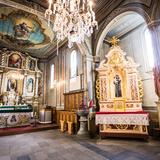 Drewniany kościół z ołtarzem głównym i bocznym, bogate zdobienia i polichromie.