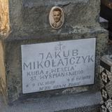 Fragment kamiennego nagrobka z jasną tablicą i napisem m.in. Jakub Mikołajczyk Kuba z 