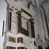Jasny ołtarz z ciemnymi kolumnami i tablicami oraz z dwiema rzeźbami, jedna nad drugą.