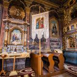 Wnętrze drewnianej cerkwi. Bogate polichromie, ołtarz boczny i fragment ikonostasu.