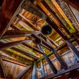 Drewniana konstrukcja stropu i dachu z wiszącym dzwonem.