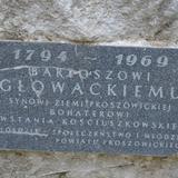 Przymocowana do kamienia tablica pamiątkowa z wyrytym napisem: 1794–1969 Bartoszowi Głowackiemu synowi ziemi proszowickiej bohaterowi Powstania Kościuszkowskiego w hołdzie społeczeństwo i młodzież powiatu proszowickiego.