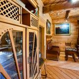 Wnętrze drewnianej willi, z kredensem drewnianym z szybami po lewej, na wprost z drewnianą kanapą, stolikiem i dwoma fotelami oraz obrazami nad nimi. Na wprost piec kaflowy.