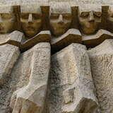 Zbliżenie od dołu na betonowy pomnik z pięcioma postaciami jedna za drugą, ze spuszczonymi głowami.